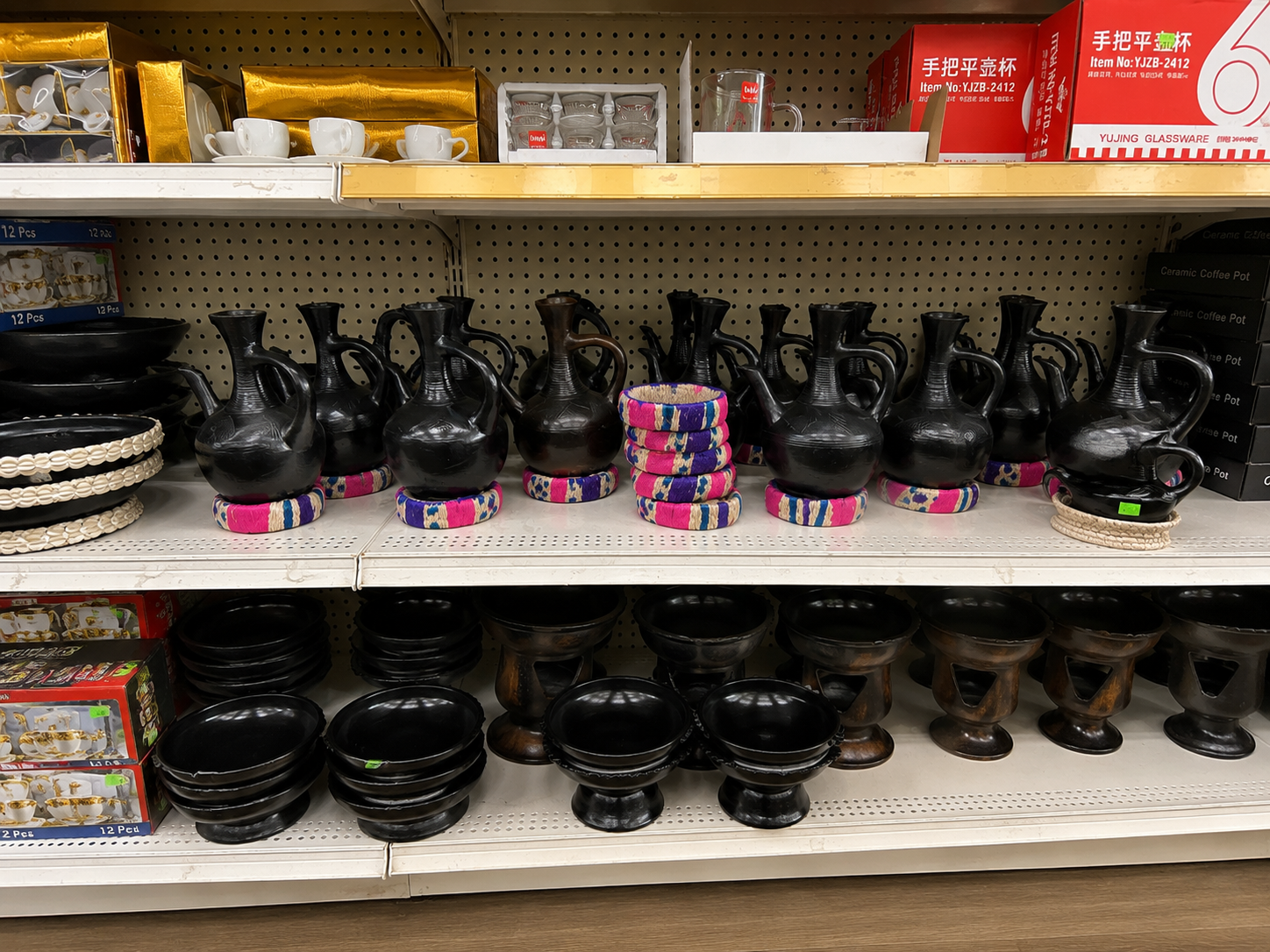 Retail display of black clay cooking pots with colorful woven handles