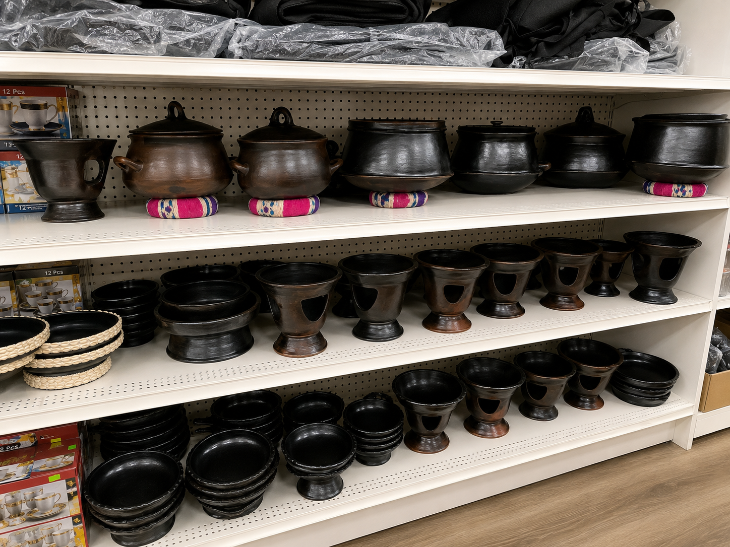 Multiple shelves with black cast iron cooking pots and serving bowls