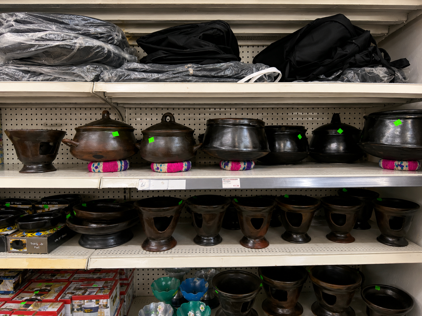 Pegboard display with black clay pots and colorful woven accents